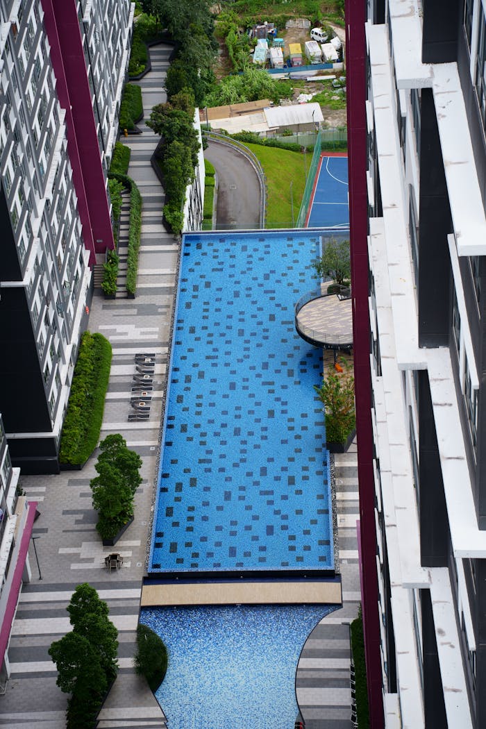 High-angle view of a luxury apartment complex featuring a blue swimming pool and garden.