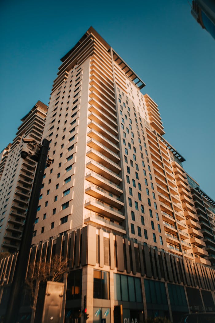 Low angle view of a modern skyscraper bathed in warm golden hour light.